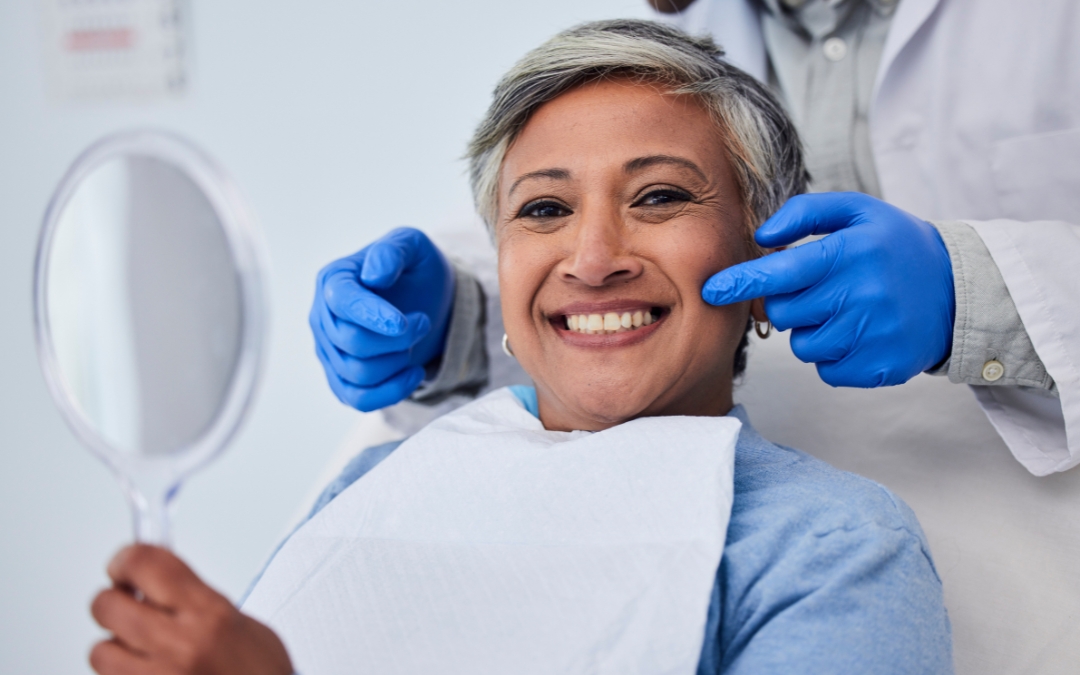 Happy mature woman admiring her smile in mirror at dental office with dentist.